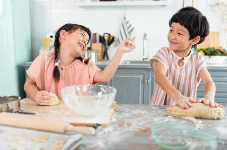Happy asian family funny kids are preparing the dough, bake cookies in the kitchen.の写真素材