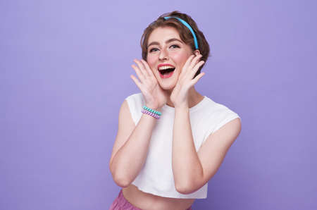 Young happy teen woman shout story or making announcement isolated on purple background.の写真素材