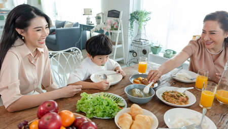 Asian happy family spend time having lunch on table together.  relationship and activity in house.