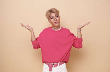 Youth asian transgender LGBT looking at camera while posing isolated over nude color background.
