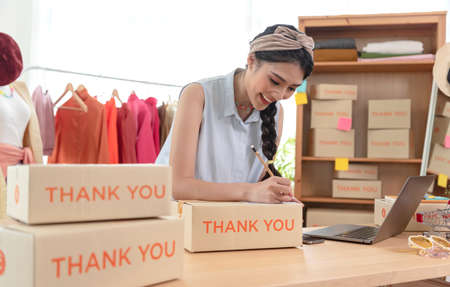 Asian young woman sell clothes entrepreneur working at home. start-up small business owner, SME or freelance business online and delivery concept.の写真素材