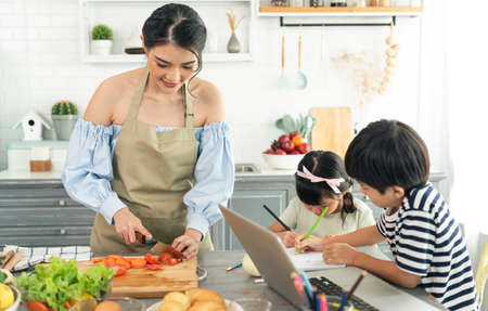 Asian young single mother making food while taking care child in kitchen. home school and single...