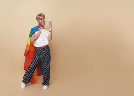 Youth asian transgender LGBT standing with finger pointing isolated over nude color background with copy space.の写真素材