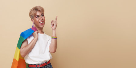 Youth asian transgender LGBT standing with finger pointing isolated over nude color background with...