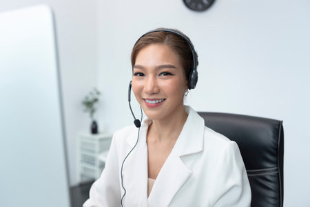 Asian woman Call center agent with headset working on support hotline in modern office with copy space.の写真素材