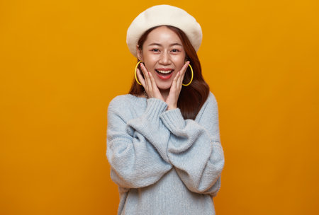 Excited asian teen woman shocked surprised isolated on studio yellow background.の写真素材