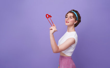 Smiling happy woman holding chopsticks showing 0% interest installment payment promotion against purple banner background.の写真素材