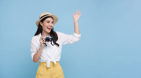 Happy smiling Woman photographer is taking images photo with dslr camera isolated studio blue background.の写真素材