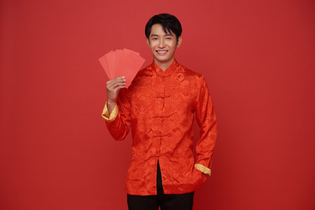 Happy Chinese new year. Asian man holding angpao or red packet monetary gift with text means great luck isolated on red background.の写真素材