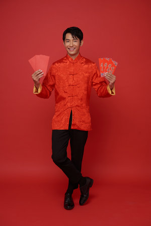 Happy Chinese new year 2024. Asian man holding angpao or red packet monetary gift isolated on red background. Chinese text means great luck great happy.の写真素材