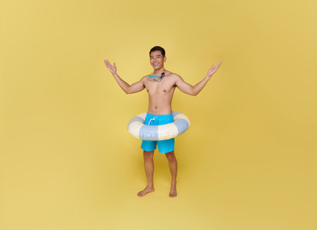 Full body young tourist asian man hold inflatable ring happy summer vacation isolated on yellow background.の写真素材
