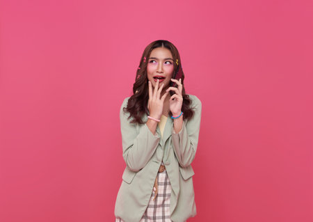Young smiling happy asian woman 20s talking mobile cell phone gossip isolated on pink background.の写真素材