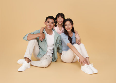 Portrait happy smiling Asian family sitting and hugging together isolated on nude color background.の写真素材