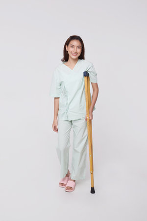 Happy Asian patient woman Use a crutch to walk due to accidental injury with awesome insurance concept.の写真素材