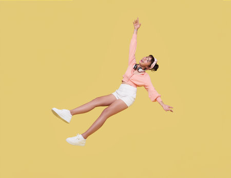 Happy smiling asian cute girl relaxing floating in mid-air isolated on yellow background.の写真素材