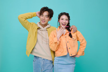 Portrait happy young Asian couple love hugging together and looking at camera isolated on blue background.の写真素材