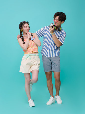 Happy young Asian couple tourist photographer is taking selfie images photo with camera to travel on summer beach holiday isolated on blue background.の写真素材