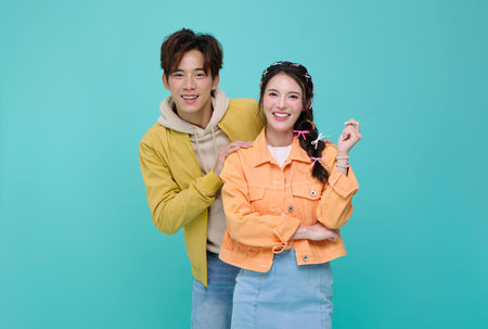 Portrait happy young Asian couple love hugging together and looking at camera isolated on blue...