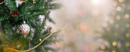 Christmas tree with silver ornament and golden garland surrounded by soft glowing bokeh lights creating a festive holiday ambiance for seasonal decoration themes and joyful xmas backgroundの写真素材