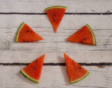 Pieces of watermelon on a white wooden background with geometric shapesの写真素材