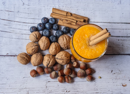 Pumpkin juice, blueberries and dried fruits on a white wooden background, vintage styleの写真素材