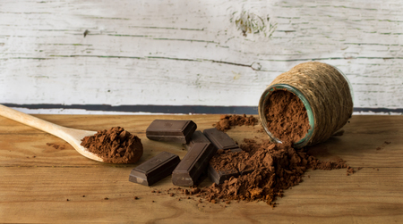 Ounces of chocolate and pure cocoa powder, on an old wooden background