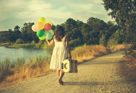 Woman with colorful balloons and suitcase in a field of Toledo, Spainの写真素材