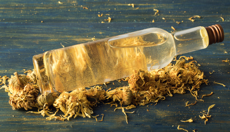 Facial tonic of calendula and chamomile and golden mica, on a wooden backgroundの写真素材