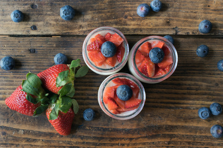 Homemade strawberry yogurt with jam and pieces of fruit on a wooden board. View from aboveの写真素材