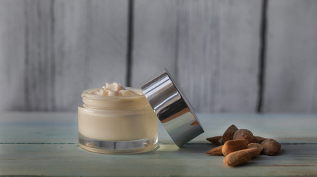 Homemade facial cream of almond oil, with natural almonds on a white wooden backgroundの写真素材
