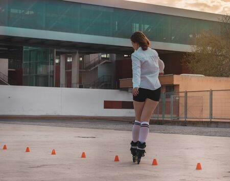 Beautiful young woman having fun with skates at sunsetの写真素材
