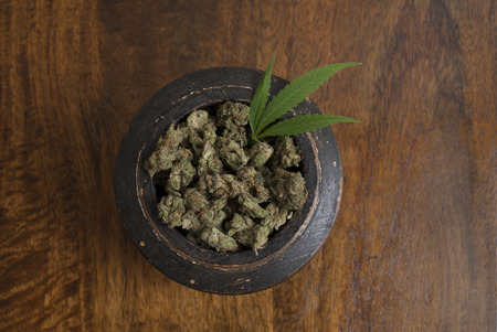 Cannabis sativa flower buds and leaf in wooden bowl, on wooden backgroundの写真素材