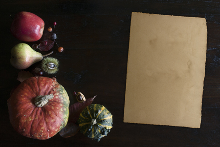 beautiful rustic fall flat lay with leaves, pumpkins, chestnuts and old vintage paper sheet  on wooden backgroundの写真素材