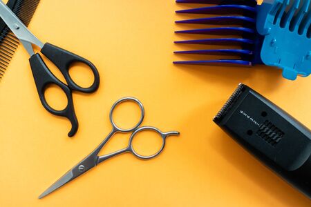 Top view of scissors, and trimmers for hair and beard on orange background.の写真素材