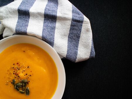 Homemade carrot creat perfect for a diet and decorated with a blue and white cloth on a dark backgroundの写真素材