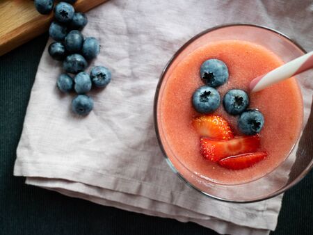 Fresh smoothie made with organic wildberries and decorated with a wooden table with some blueberries.の写真素材
