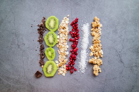 Vegan and organic ingredients for a healthy snack: Kiwi, pomegranate, chocolate, coconut, oats and...