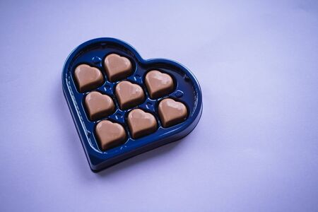 Chocolate bonbons with heart shape on purple background. Saint Valentine's concept.の写真素材