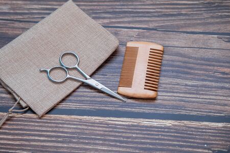 Scissors and comb for trimming a perfect beard on wooden background. Close up view.の写真素材