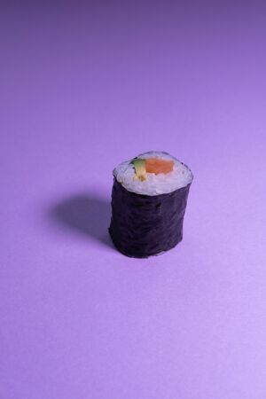 Avocado and salmon maki sushi isolated on purple background. Vertical concept picture. Japan food.の写真素材