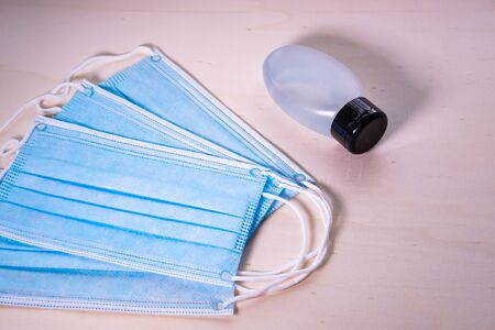 Surgery face masks and hand satnitizer gel on wooden background. Items to prevent coronavirus....