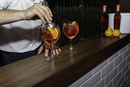 Young man preparing a delicious martini with orange ready to be enjoyedの写真素材