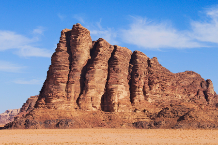 Seven pillars of wisdom on Wadi Rum desert in Jordan. Around red sand and clear blue sky with few clouds.の写真素材