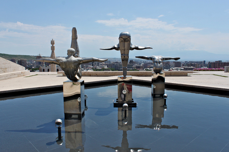 Armenia, Yerevan; July 9th 2014 - Modern art. Stainless steel sculptures of three athletes on top of Cascades in front of entrance door to a museum in Yerevan. Panarama of the city.のeditorial素材