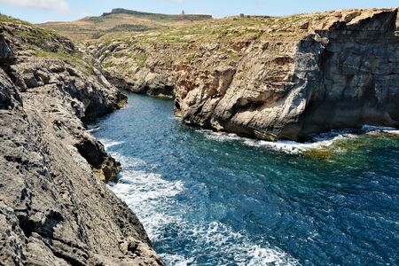 Wied il-Ghasri gorge surrounded by high clifs meets blue waters of the Mediterranean Seの写真素材