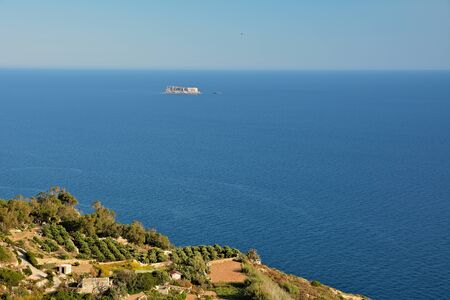 View from Dingli Cliffs on Malta. Rocky terrain with blue waters of Mediterranean Sea and small island on the horizon.の写真素材