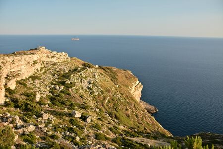View from Dingli Cliffs on Malta. Rocky terrain with blue waters of Mediterraean Sea and small island on the horizon.の写真素材