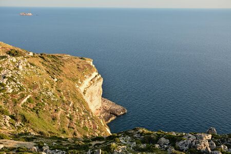 View from Dingli Cliffs on Malta. Rocky terrain with blue waters of Mediterraean Sea and small island on the horizon.の写真素材