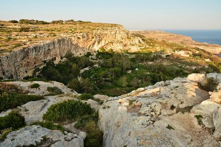 View from Dingli Cliffs on Malta. Rocky terrain with blue waters of Mediterraean Sea and small island on the horizon.の写真素材