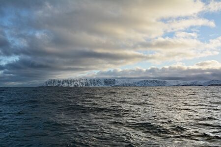 Nordkapp is a municipality in Norway. It is 307-metre-high cliff that is commonly referred to as the northernmost point of Europe. However, the true northernmost point of the European mainland is Cape Nordkinn. View from a sailing boat on snowy hills.の写真素材